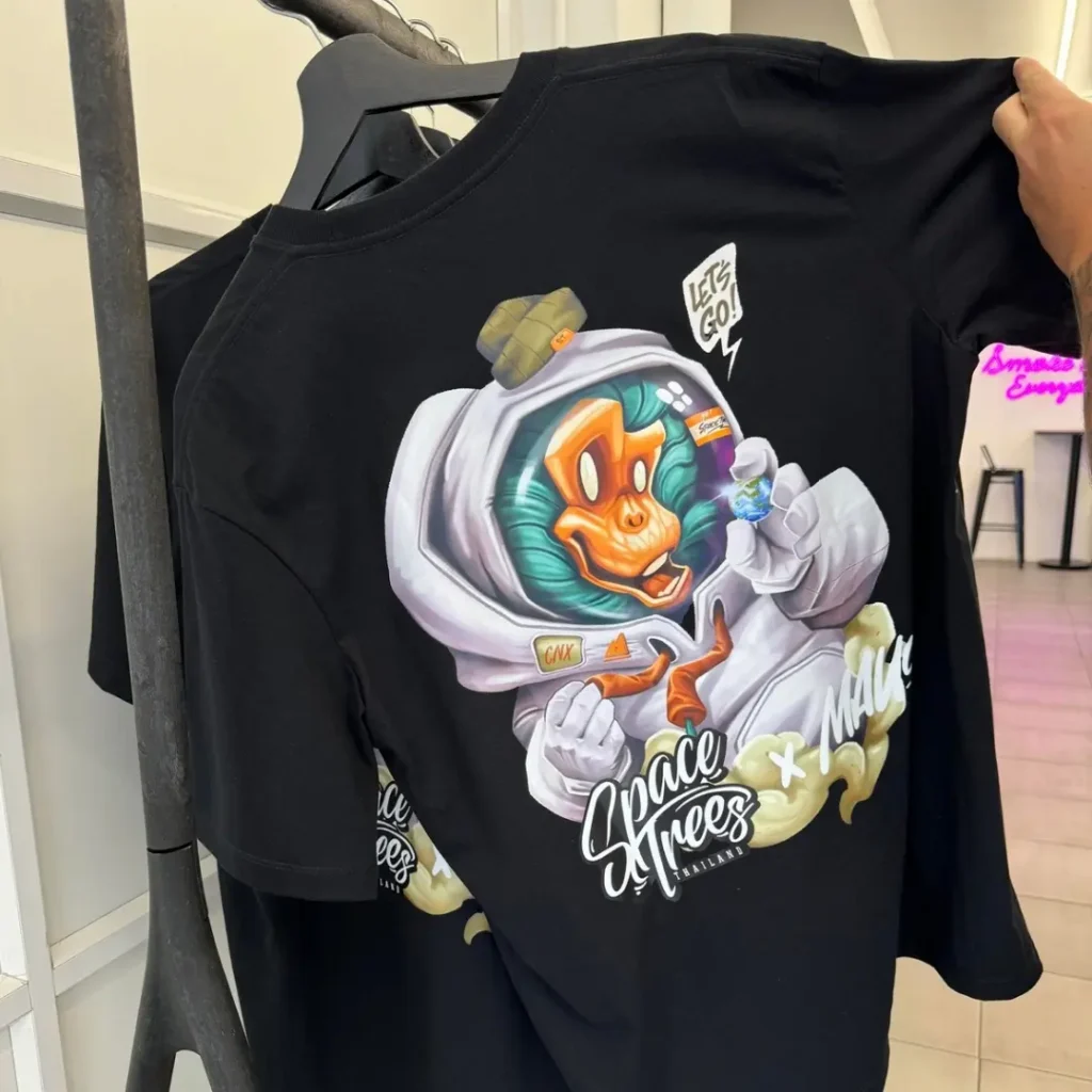 Space Trees dispensary merchandise featuring a black t-shirt with custom astronaut monkey design at the Chiang Mai location